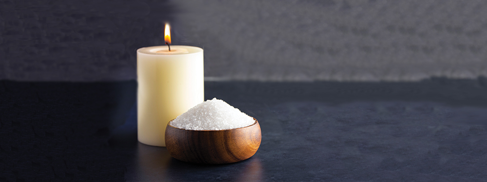 Picture of a candle and a measure of salt on a table.